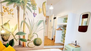 A breakfast setup with a tray, coffee, juice, and pastries in a room with a tropical-themed wall mural and a mirror. - Napoli Tree - Lungomare (Naples)