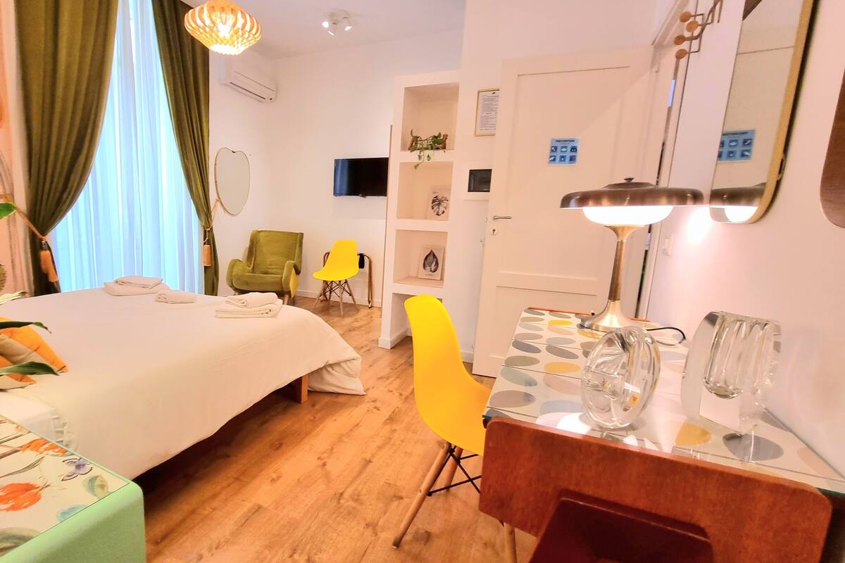 Une chambre d’hôtel avec un lit, un bureau, une chaise, une télévision et un miroir.