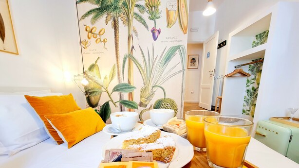 A hotel room with a bed, breakfast tray, and a tropical-themed wall mural. - Napoli Tree - Lungomare (Naples)