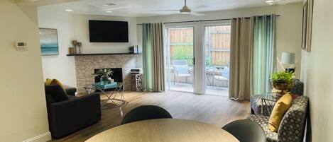 Una sala de estar moderna con chimenea, un comedor con mesa redonda y un ventanal con cortinas.