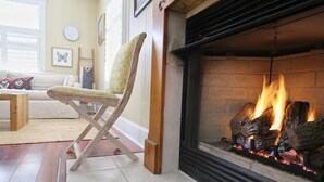Ein gemütliches Wohnzimmer mit Kamin, einem Holzstuhl, einer Couch und einem kleinen Tisch.