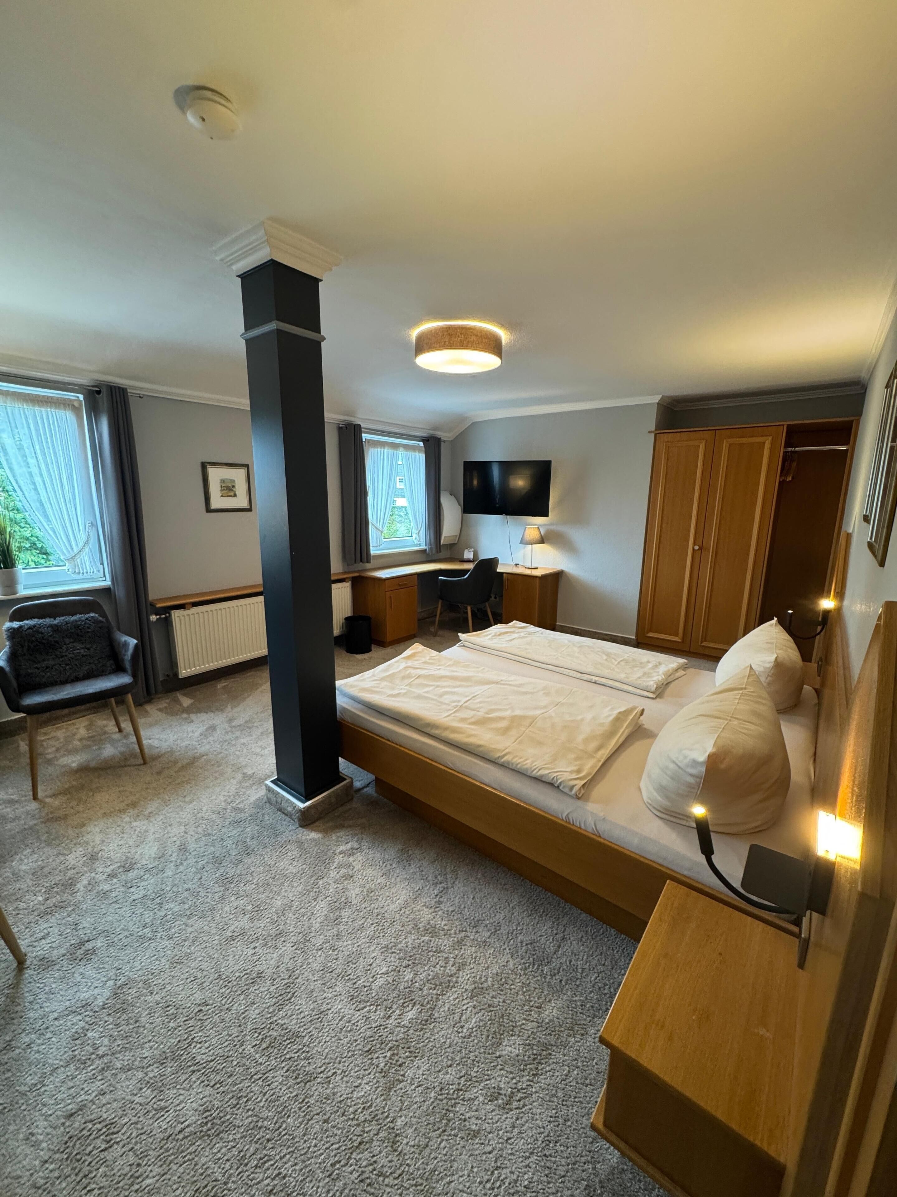 Ein Schlafzimmer mit einem Bett, einem Schreibtisch, einem Stuhl, einem Fernseher und einem Kleiderschrank.