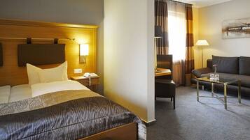 A hotel room with a bed, bedside table, lamp, and a sofa area with a coffee table.