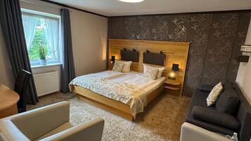 A hotel room with a large bed, two bedside tables, a sofa, and a chair.