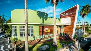 Un edificio con fachada verde, un letrero que dice 'mellow mushroom' y palmeras.