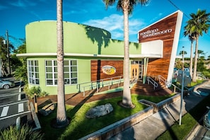 A building with a green facade, a sign reading 'mellow mushroom,' and palm trees.