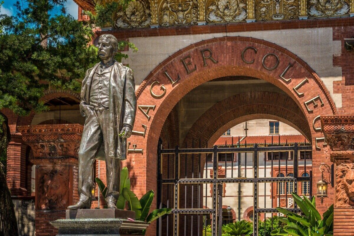 A statue in front of a brick archway with the inscription 'AGLER COLLEGE'.