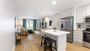 Una cocina moderna con una isla central, electrodomésticos de acero inoxidable y vistas a un balcón.