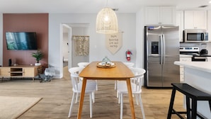 Una cocina moderna con armarios blancos, un refrigerador de acero inoxidable y un microondas.