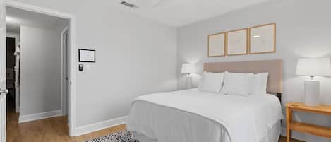 A bedroom with a bed, bedside lamps, a ceiling fan, and a patterned rug.