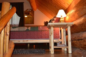 A cozy log cabin room with a wooden bed, a small table with a lamp, and a stuffed rabbit toy. - Cabin In The Wildwood (Chehalis)