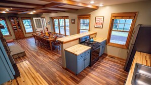Una cocina amplia con pisos de madera, comedor y ventanas grandes.