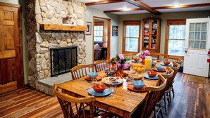 Comedor con chimenea de piedra, mesa de madera y sillas.