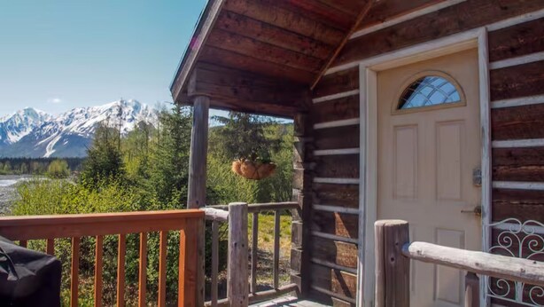 Eine Holzhütte mit Veranda, Tür und Blick auf die Berge.