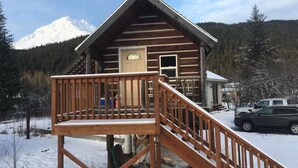 Eine Blockhütte mit einer Holzterrasse und einer Treppe zum Eingang.