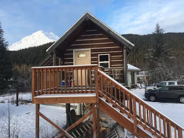 A log cabin with a wooden deck and a staircase leading to the entrance.