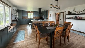 A modern kitchen with a central island, wooden dining table, and chairs. - Cottage on a Lake.  Near Pictured Rocks/ Munising (Manistique)