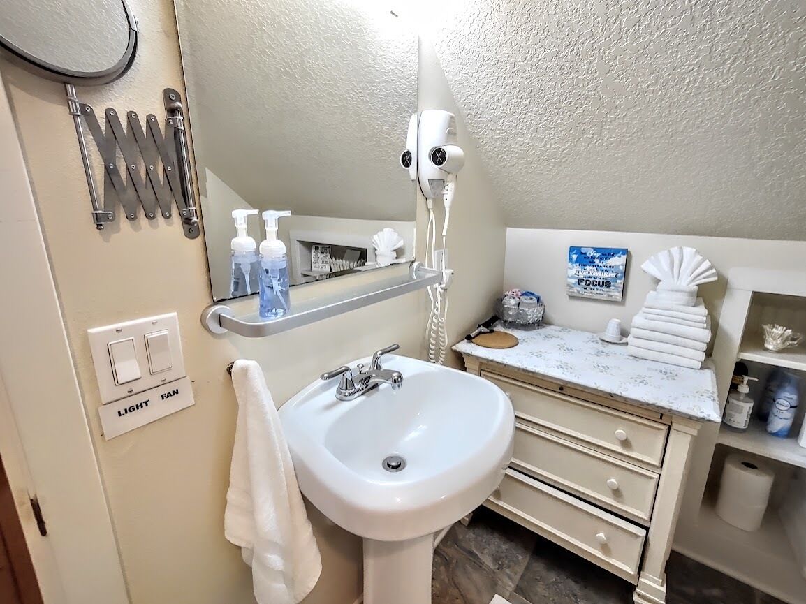A bathroom with a sink, mirror, towel rack, and toiletries.