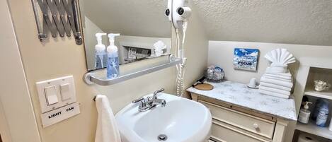A bathroom with a sink, mirror, towel rack, and toiletries.