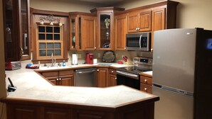 A kitchen with wooden cabinets, a stainless steel refrigerator, a microwave, an oven, and a dishwasher.