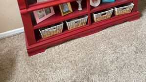 Eine rote Unterhaltungseinrichtung mit einem Flachbildfernseher, Regalen mit Dekoration und Korbwäsche.