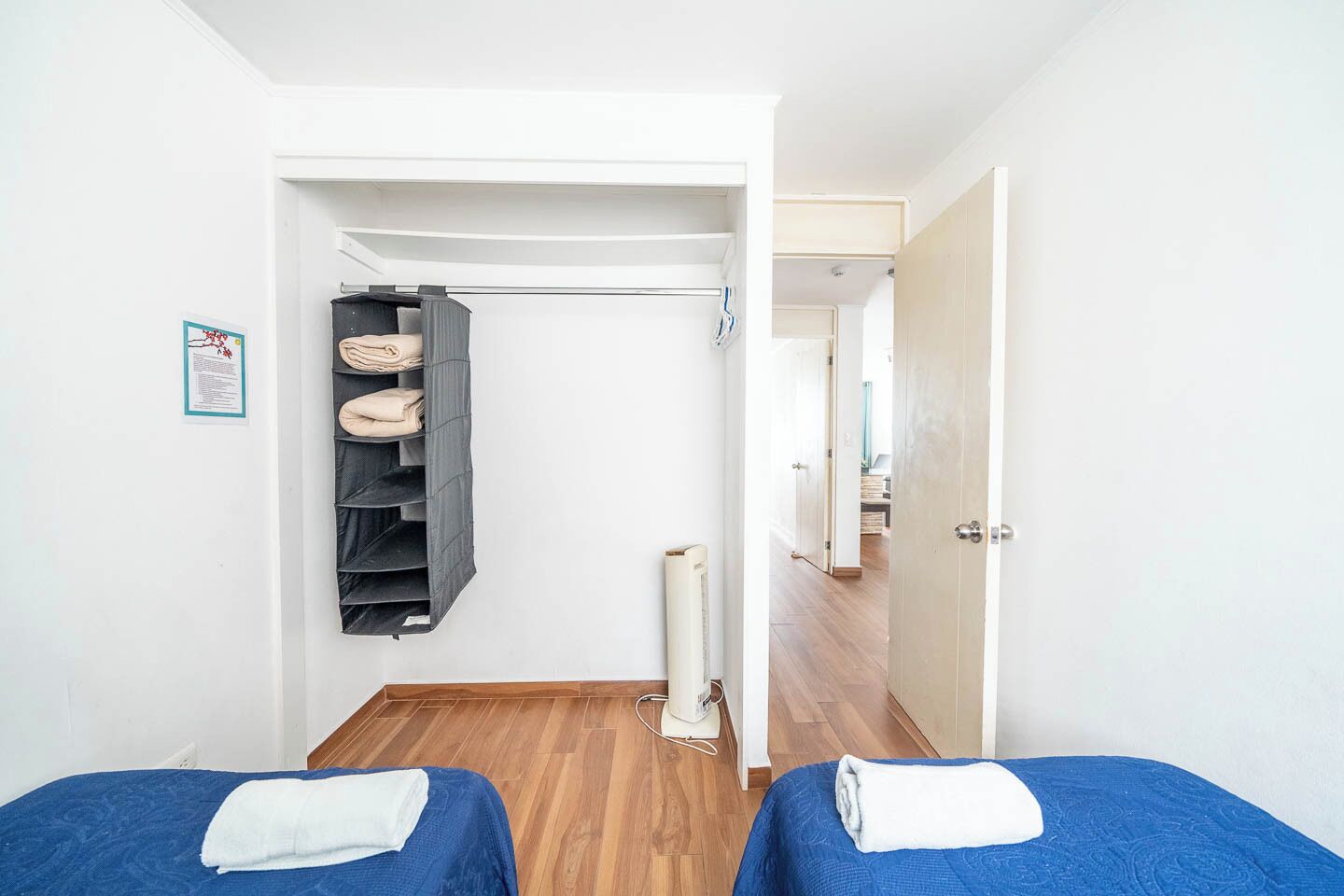 A hotel room with two beds, a wardrobe, and a radiator.