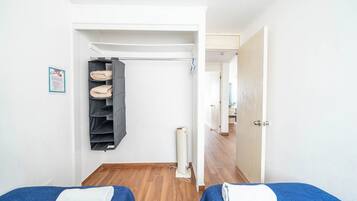 A hotel room with two beds, a wardrobe, and a radiator.