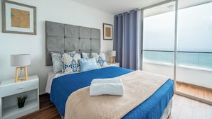 Ein modernes Schlafzimmer mit einem großen Bett, Meerblick und einem Balkon.