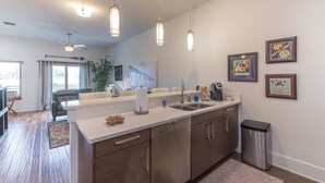 A modern kitchen with a central island, stainless steel appliances, pendant lighting, and framed artwork on the wall.