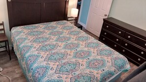 Una camera da letto con un letto, una cassettiera, una sedia e una porta.