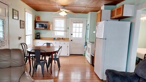 Una cucina compatta con zona pranzo, soffitto in legno e frigorifero.