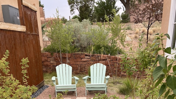 A garden area with Adirondack chairs, a gravel path, and a stone wall. - Contemporary Guest House--Close In, Great Views (Santa Fe)