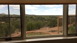 A room with a large window overlooking a landscape with trees and a distant hill. - Contemporary Guest House--Close In, Great Views (Santa Fe)