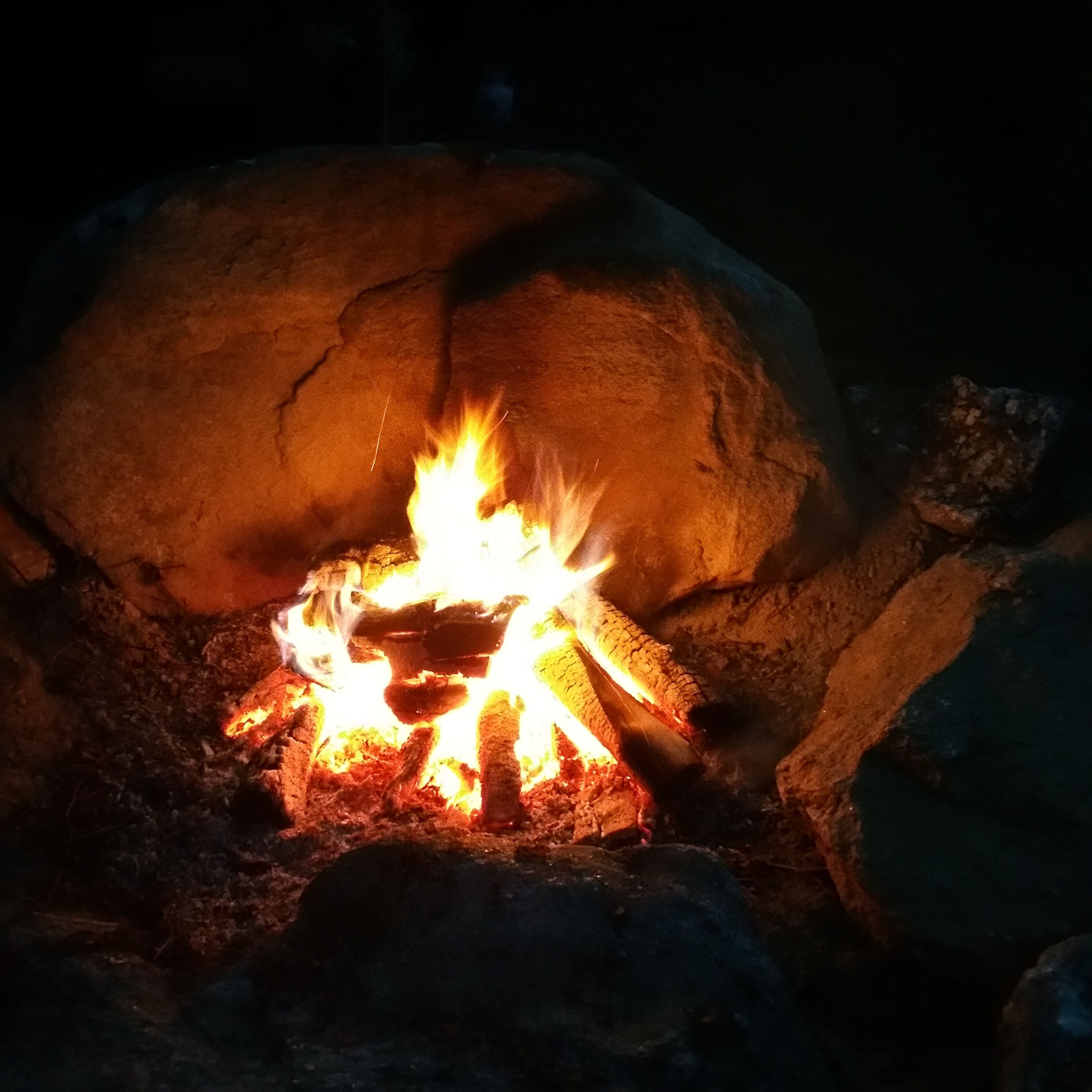 A campfire burning inside a rock structure.