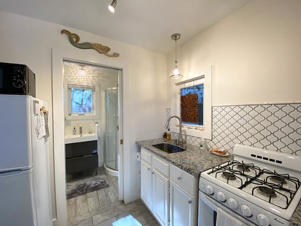A modern kitchen with white cabinets, a granite countertop, a gas stove, and a built-in oven. - Unique Zen Tiny House 2 mi to Beach ~ Free Bikes! Minutes to Historic Charleston (Mount Pleasant)