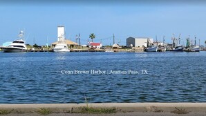 Un puerto deportivo con barcos amarrados, un edificio con techo rojo y una palmera.