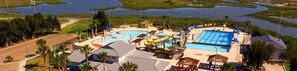 Vista aérea de un parque acuático con múltiples piscinas, toboganes y una piscina central grande.