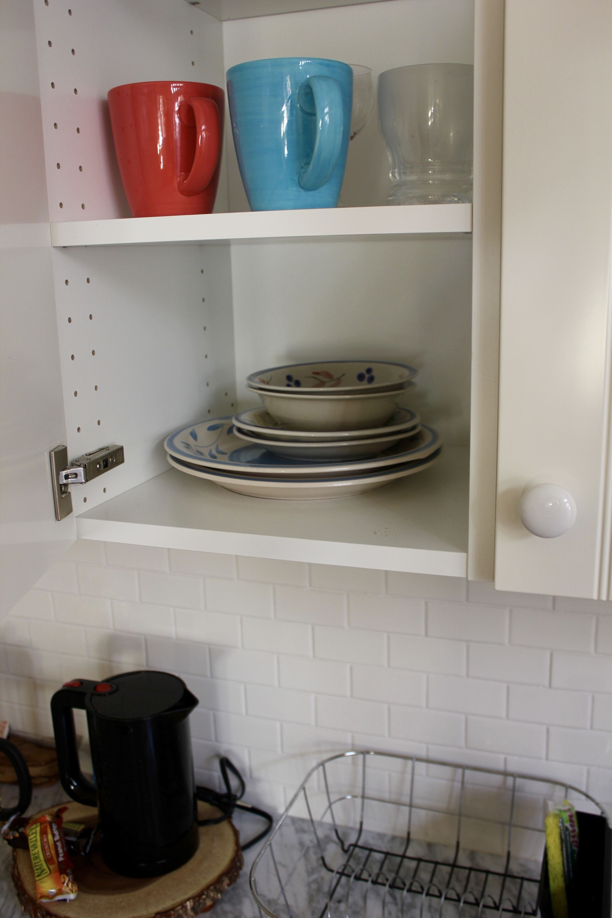 A kitchen with white cabinets, a coffee maker, and a metal rack.
