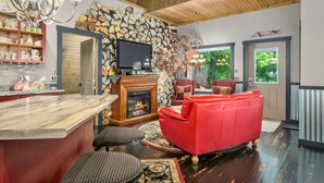 A cozy living room with a fireplace, red sofa, and a stone wall.