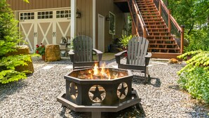 A fire pit with chairs, a staircase, and a building in the background.