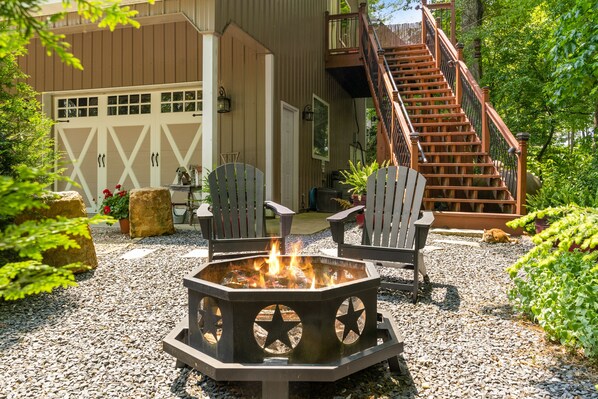 A fire pit with chairs, a staircase, and a building in the background.
