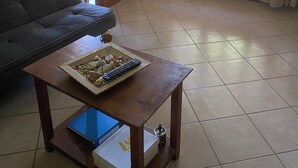 A living room with a sofa, a wooden coffee table with a remote control, a laptop, and a box. - Vacation Home in Chania,private Pool beachfront , it is consisted of 2 houses.  (Chania)