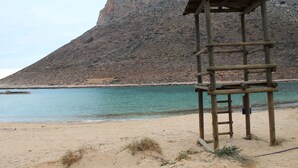 A wooden observation tower on a beach with a rocky mountain in the background. - Vacation Home in Chania,private Pool beachfront , it is consisted of 2 houses.  (Chania)