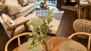 A living room with a sofa, coffee table, and chairs, a fireplace, and a balcony with a view.