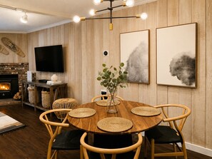 A dining area with a round wooden table, woven placemats, and wooden chairs.