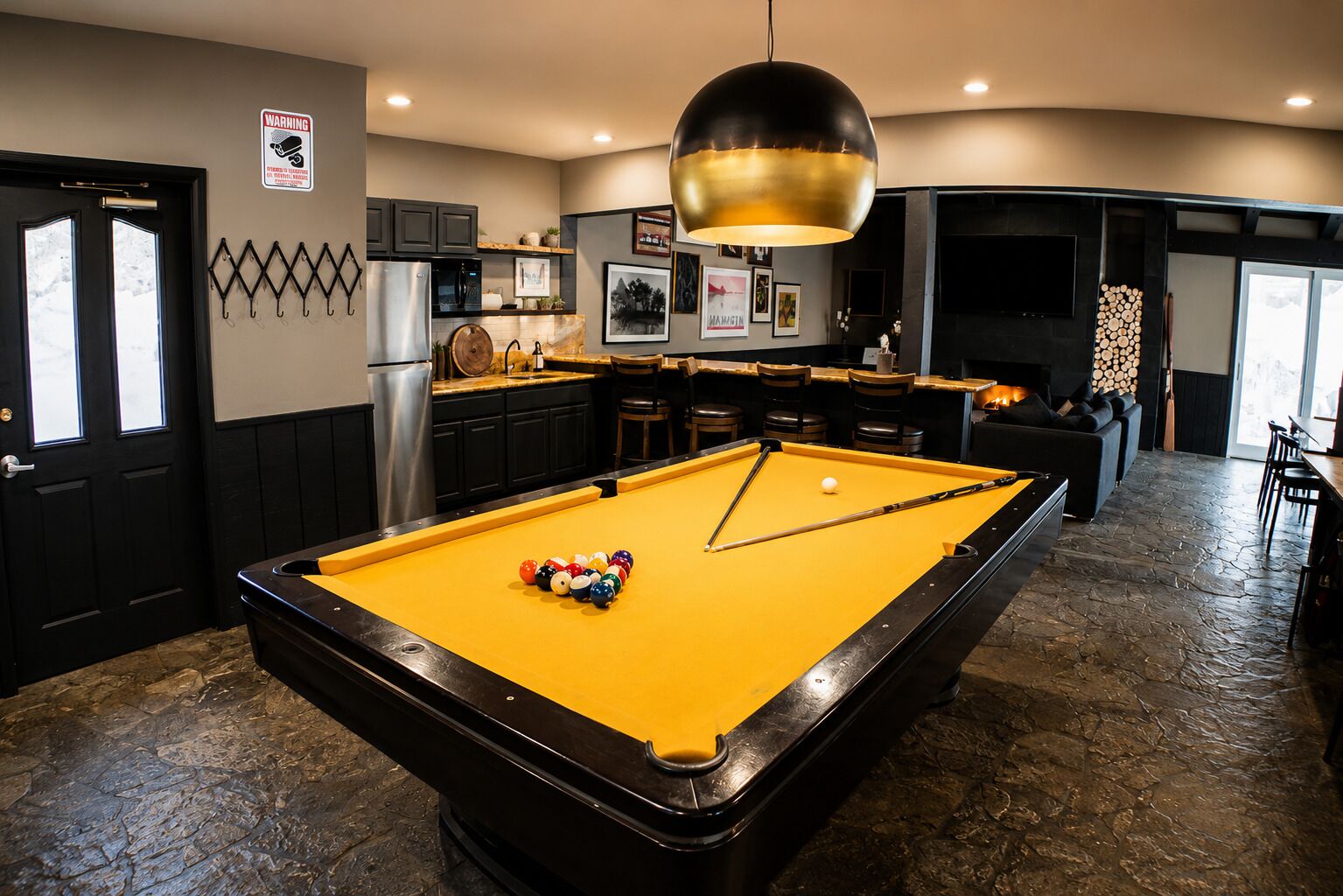 A pool table with a yellow felt surface, a black-framed pool table, and a cue stick in the center.
