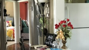Eine Küche mit Marmorarbeitsplatte, einer Vase mit roten Tulpen und einem Schild mit der Aufschrift 'Bitte unser Gästebuch unterschreiben', sowie ein Flur, der zu einem Schlafzimmer führt.