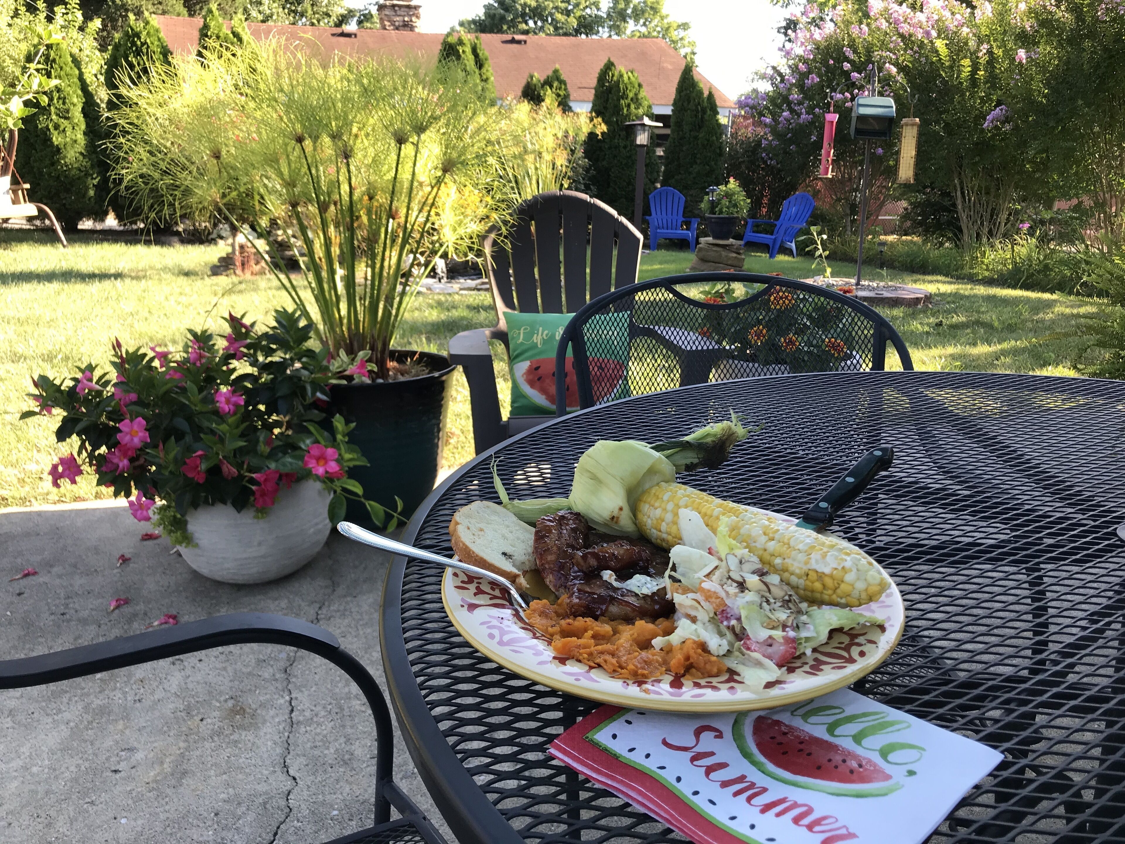 A patio with a metal table, a plate of food, and a watermelon-themed placemat.