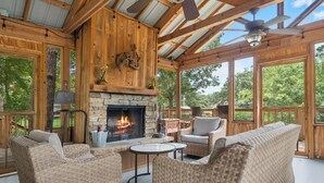 A wooden deck with wicker furniture, a stone fireplace, and a ceiling fan. - “Fun” place! — Exceptional" —near Oaklawn Park, Garvin Gardens and Restaurants (Hot Springs)
