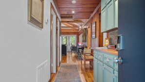 A hallway with wooden floors, a patterned rug, and light blue cabinets. - “Fun” place! — Exceptional" —near Oaklawn Park, Garvin Gardens and Restaurants (Hot Springs)